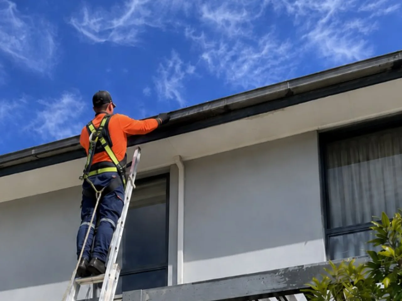 Gutter cleaning technician carrying a ladder to access a double-storey Perth home