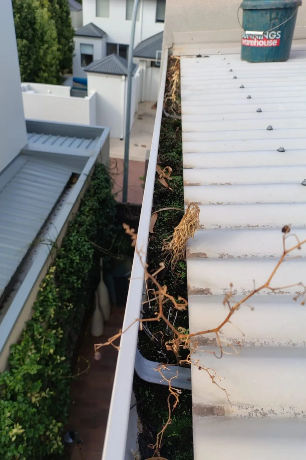 Gutter cleaner clearing a patio gutter above an outdoor entertaining area in Perth
